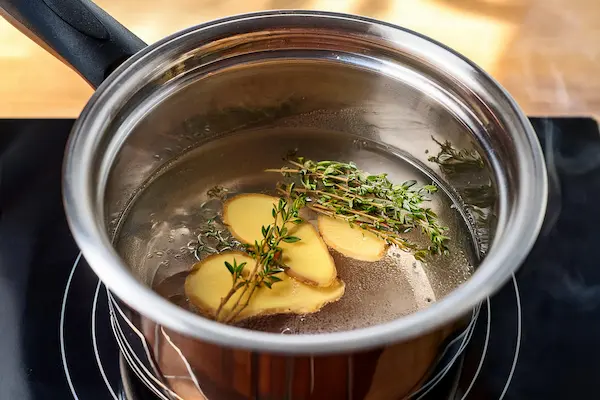 a small saucepan with sliced ginger and springs of thyme for making homemade honey