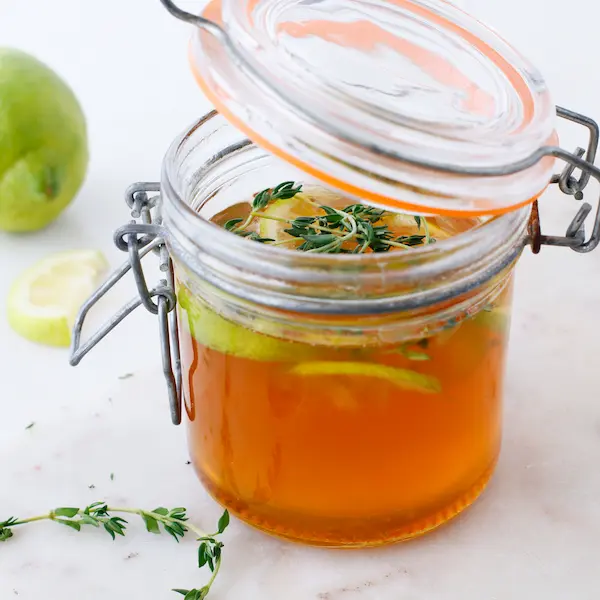 a jar with a lid of homemade thyme, ginger, lemon and honey cough syrup