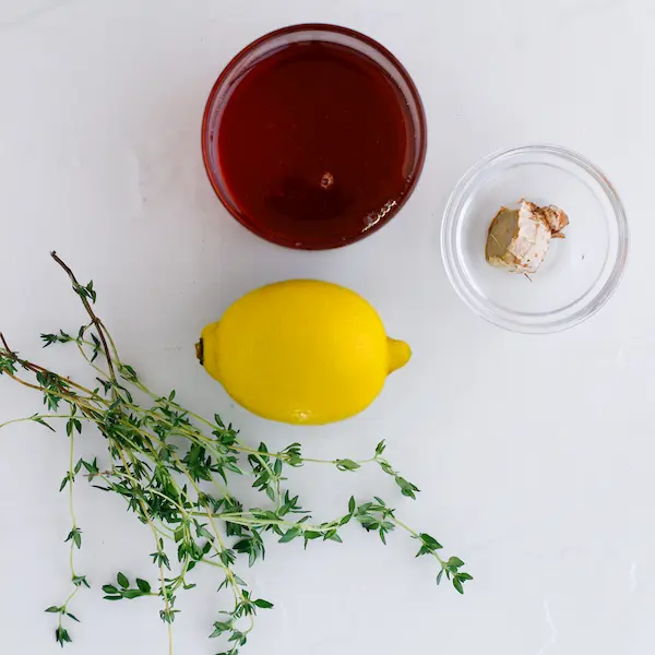 a lemon, honey, ginger, and thyme on a white background for making a homemade cough syrup